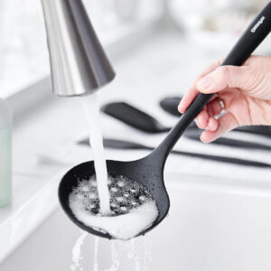 Black silicone kitchen utensils with stainless handles on countertop