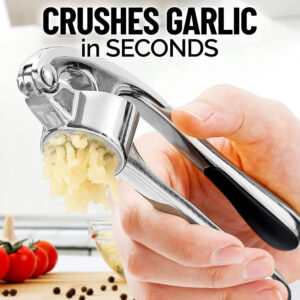 Garlic press placed on cutting board with garlic, ginger, and herbs